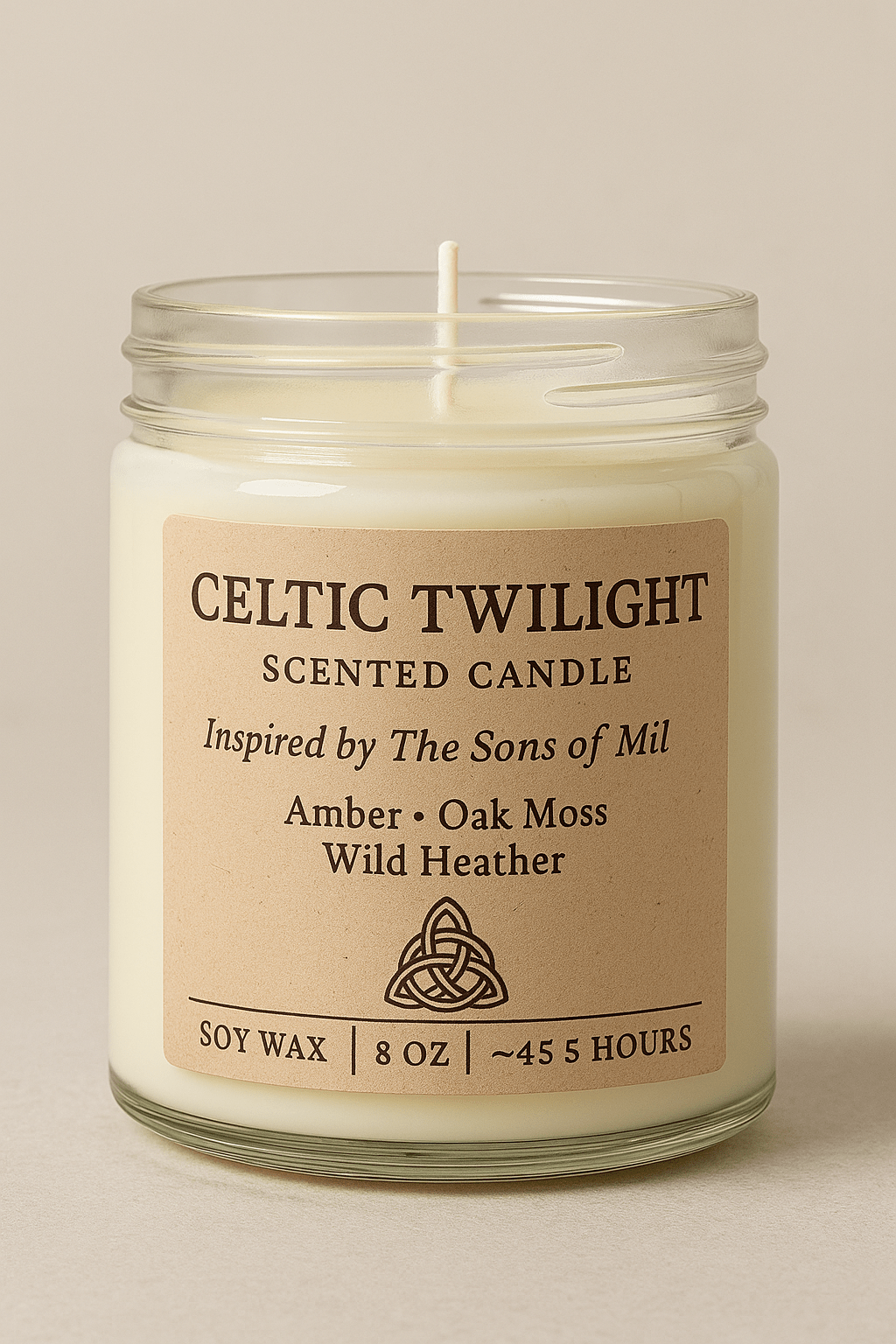 A Celtic Twilight scented candle in a clear glass jar with a beige label displaying the text “Inspired by The Sons of Mil – Amber, Oak Moss, Wild Heather.” The candle features a single cotton wick and natural soy wax, photographed against a soft neutral background for an elegant, minimalist look.