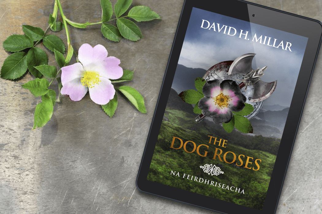 "The Dog Roses" by David H. Millar displayed on an e-reader, surrounded by a pink dog rose and green leaves on a textured surface.